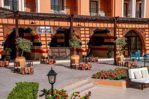 Lounge-Bereich des Jaz Lamaya Resorts mit bunten Tischen, Stühlen und Blumenbeeten.