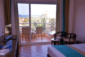 Zimmer im Utopia Beach Club Hotel mit Blick auf das Meer und eine Terrasse mit Möbeln.