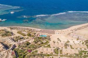 Utopia Beach Club Außenansicht mit Strand, Meer und Gebäuden.