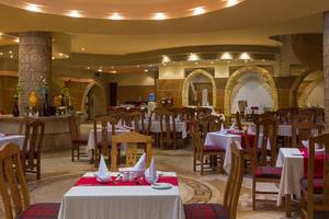 Innenansicht des Restaurants im Utopia Beach Club mit runden Tischen und Stühlen, dekorierten Tischen und architektonischen Bögen.