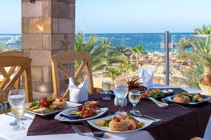 Utopia Beach Club mit Blick auf das Meer und einer servierten Mahlzeit auf dem Tisch.