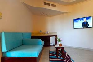 Wohnbereich im Utopia Beach Club Hotel mit blauem Sofa, Tisch, Fernseher und Blumen.