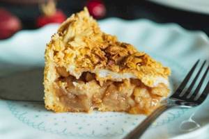Eine Schnitte Apfelkuchen auf einem Teller mit einer Gabel.