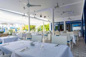 Innenbereich des Restaurants im Anonymous Beach Hotel mit gedeckten Tischen und Stühlen.