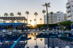 Sonnenuntergang am Swimmingpool des Anonymous Beach Hotels mit Lounge-Stühlen und Palmen.