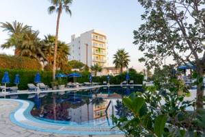 Der Außenpool des Anonymous Beach Hotels mit Lounge-Stühlen, Sonnenschirmen und Palmen.