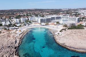 Luftaufnahme des Anonymous Beach Hotels mit Blick auf den Strand, Gebäude und kristallklares Wasser.
