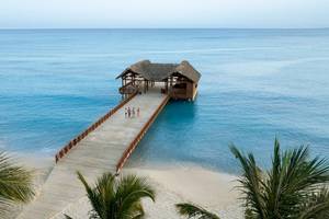 Ein Hotel am Strand der Dominikanischen Republik mit einer Holzbrücke und einer Hütte