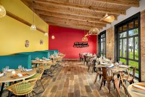 Innenbereich des Restaurants Sunscape Dominicus La Romana mit bunten Wänden, Holzboden und Tischdekoration.