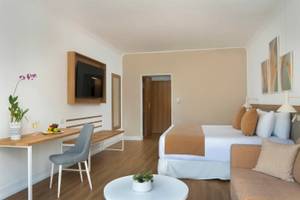 Innenansicht eines Zimmers im Sunscape Dominicus La Romana Hotel mit einem Bett, Schreibtisch, Sofa und Fernseher.