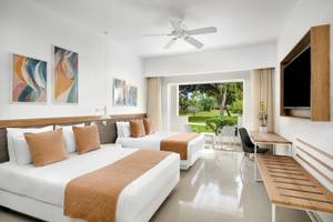 Doppelzimmer im Sunscape Dominicus La Romana mit zwei Betten, Klimaanlage, Fernseher und Fenster zur Terrasse.