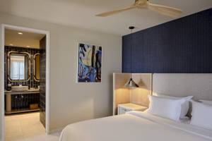 Schlafzimmer im Atlantica Kalliston Resort mit einem großen Bett, weißen Kissen und einer modernen Wanddekoration.