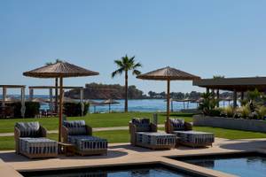 Lounge-Sessel am Pool des Atlantica Kalliston Resorts mit Blick auf das Meer.