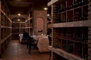 Weinkeller des Atlantica Kalliston Resorts mit gefüllten Regalen und gedeckten Tischen.