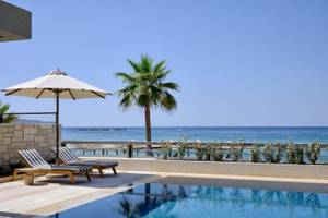 Pool-Terrasse des Atlantica Kalliston Resorts mit Blick auf das Meer und Sonnenschirmen.