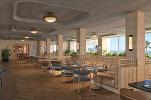 Innenansicht des Restaurants im Atlantica Kalliston Resort mit Holzboden und großen Fenstern.