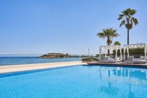 Ein Swimmingpool im Atlantica Kalliston Resort mit Liegen und Blick auf das Meer
