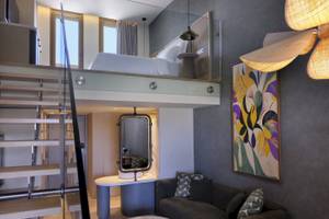 Innenansicht eines Zimmers im Atlantica Kalliston Resort mit hoher Decke, Doppelbett und Wohnzimmerbereich.