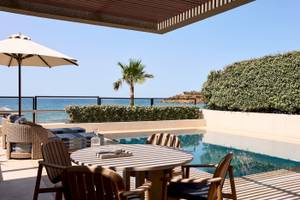 Terrasse mit Meerblick im Atlantica Kalliston Resort mit Tisch, Stühlen und Sonnenschirm.