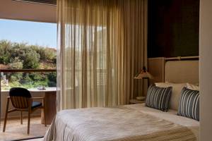 Zimmer im Atlantica Kalliston Resort Hotel mit Bett und Stuhl vor dem Fenster