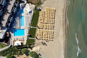 Atlantica Kalliston Resort, Blick auf das Hotel am Strand mit Pool und vielen Sonnenschirmen.