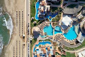 Luftaufnahme des Außenbereichs des Atlantica Kalliston Resorts mit mehreren Swimmingpools und Sonnenschirmen.