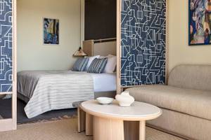 Innenansicht eines Hotelzimmers im Atlantica Kalliston Resort mit Bett, Couch und Dekoration.