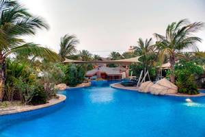 Außenansicht des Jumeirah Beach Hotel Pools mit Loungeliegen und Pflanzen.
