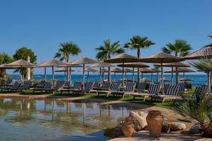 Atlantica Kalliston Resort Strand mit Lounge-Stühlen und Sonnenschirmen