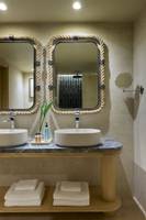 Badezimmer des Atlantica Kalliston Resorts mit zwei Waschbecken und Spiegeln.