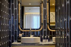 Badezimmer des Atlantica Kalliston Resorts mit schwarzer Fliesenwand und Spiegeln, die mit Seilen verziert sind.