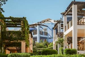 Außenbereich des Candia Park Village Hotels mit blauen und weißen Gebäuden und grünen Büschen