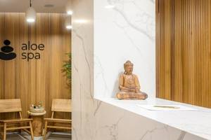 Arminda Hotel & Spa Innenbereich mit Holzwänden, zwei Holzstühlen und einer Buddha-Statue auf der Theke.