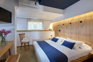 Schlafzimmer im Arminda Hotel & Spa mit einem Bett, Holzwand, Fernseher, Stuhl, und Tisch.