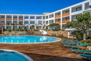 Außenpool mit Sonnenliegen und Blick auf das Arminda Hotel & Spa.