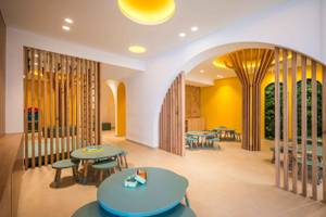 Innenbereich des Arminda Hotel & Spa mit blauen Tischen, hölzernen Trennwänden und gelben Wänden.