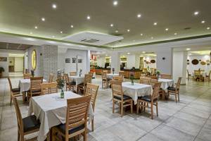 Arminda Hotel & Spa Innenbereich Restaurant mit weißen Tischen und Stühlen.