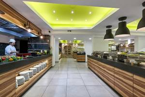 Innenansicht des Restaurants des Arminda Hotel & Spa mit einem Koch, der Gerichte zubereitet.