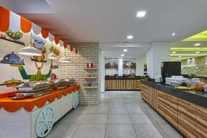 Frühstücksbereich im Arminda Hotel & Spa mit gedeckten Tischen, Buffet-Stationen und farbenfroher Wandgestaltung.