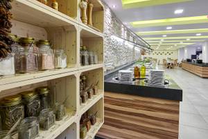 Innenbereich des Arminda Hotel & Spa mit Regalen voller Gewürzgläser und einer Theke mit gestapelten Tellern.