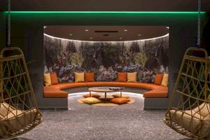 Loungebereich im Arminda Hotel & Spa mit geschwungenem Sofa und tropischem Wandbild.