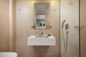 Badezimmer des Corissia Beach Hotels mit einer Duschkabine und einem Spiegel.