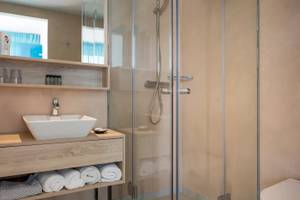 Badezimmer im Corissia Beach Hotel mit Glasdusche, Waschbecken und Handtüchern