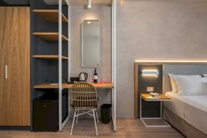 Innenansicht eines Zimmers im Corissia Beach Hotel mit Schreibtisch, Stuhl, Kühlschrank und Spiegel.