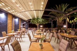 Außenbereich des Corissia Beach Hotels mit beleuchteten Tischen und Stühlen.