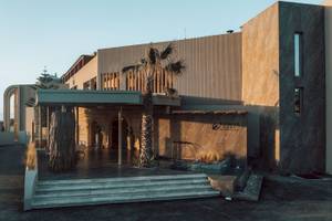 Außenansicht des Eliros Mare Hotels mit Eingang, Palme und Wasserbrunnen.