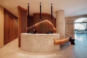 Rezeptionsbereich des Eliros Mare Hotels mit einer Theke, zwei Computern, und einer Frau dahinter.