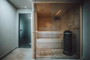 Eine hölzerne Sauna mit offenem Eingang und einer Heizeinheit in einem modernen Hotel.