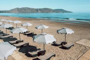 Strand des Eliros Mare Hotels mit Sonnenschirmen und Liegestühlen am Meer