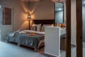 Schlafzimmer im Eliros Mare mit Bett, Decken, Kissen, Spiegel und Lampe.